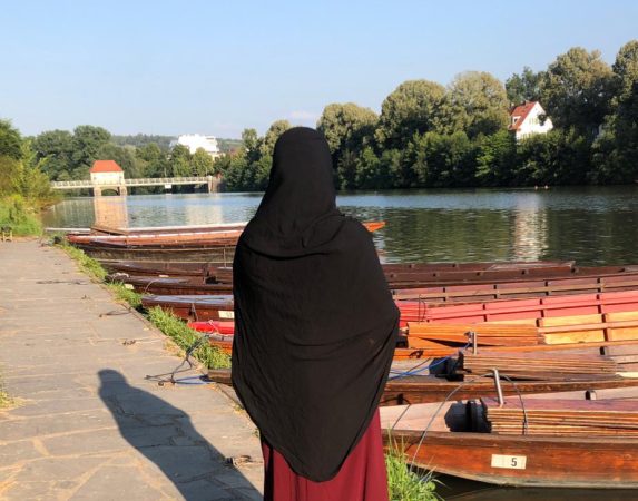 Erzieherin steht am Ufer und betrachtet den Fluss.